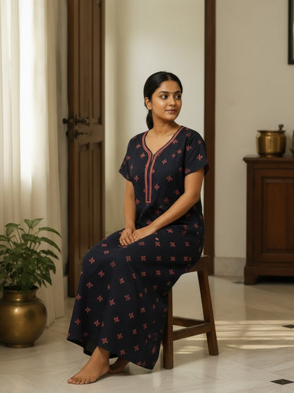 Kishona navy blue cotton nightdress with pink floral motifs and embroidered neckline worn by a woman sitting on stool