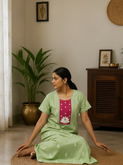 Kishona pastel green cotton maxi dress with a pink lotus-motif yoke and white patterns, worn by a woman indoors.
