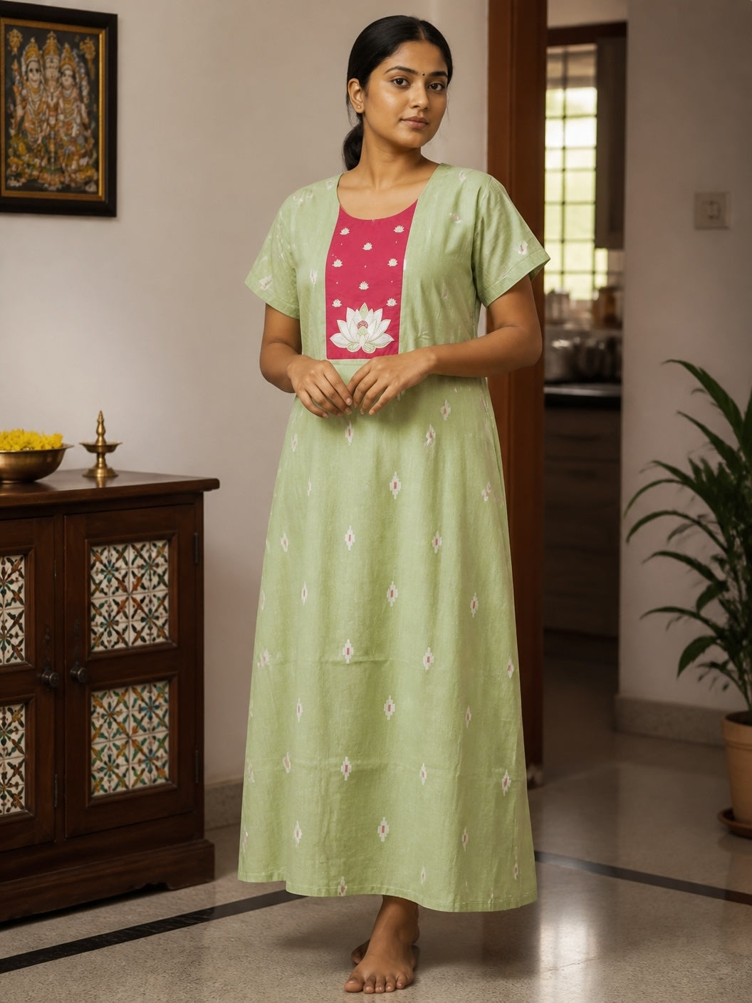 Kishona pastel green cotton maxi dress with a pink lotus motif yoke and white scattered patterns, worn by a woman.